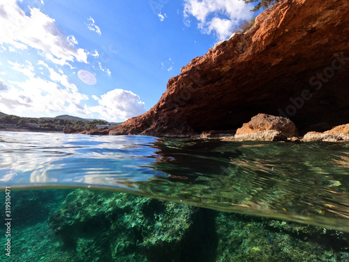 Split underwater photo of exotic island cave with rocky emerald seascape