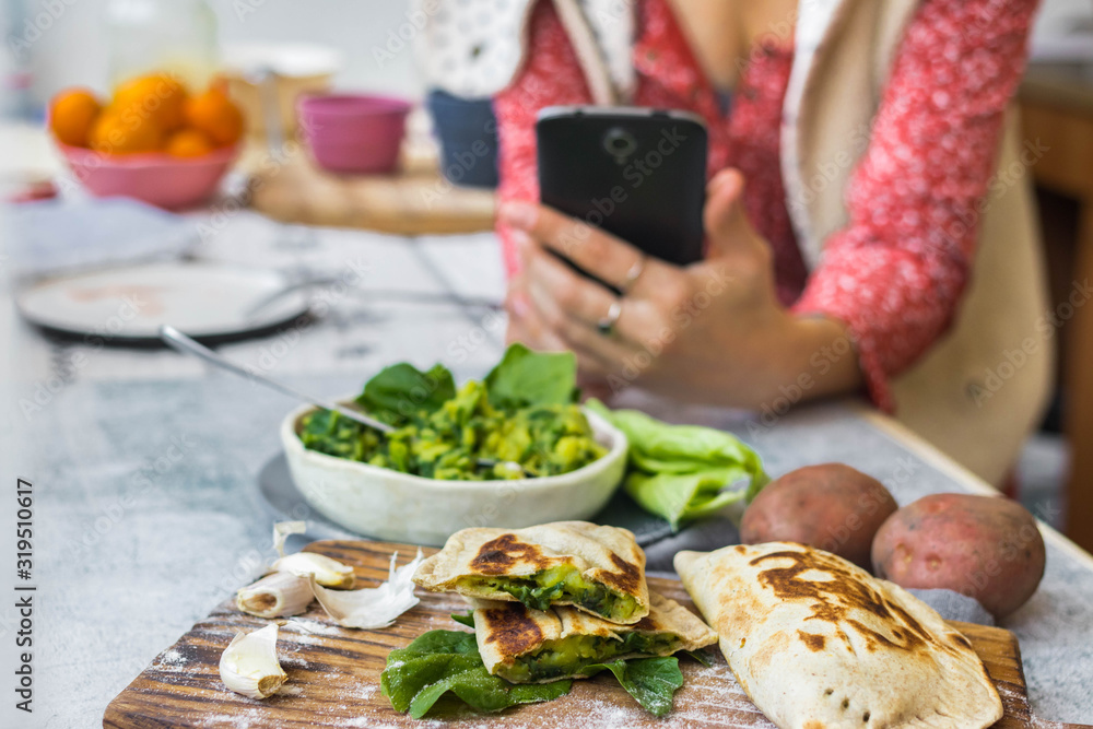 Woman take picture of vegan food with phone at her kitchen. Hand make a closeup smartphone photo of green salad and stuffed bread for blogging or social media content. Vegetarian healthy food. Woman take picture of vegan food with phone at her kitchen. Hand make a closeup smartphone photo of green salad and stuffed bread for blogging or social media content. Vegetarian healthy food.