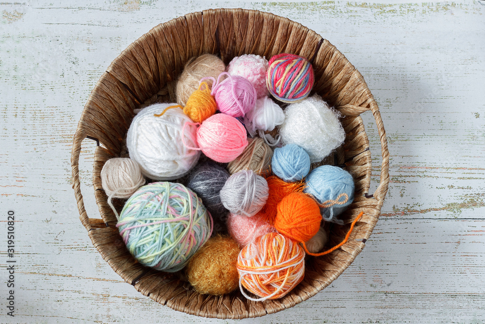 Colored threads for knitting in a basket on a wooden background. Knitting concept.