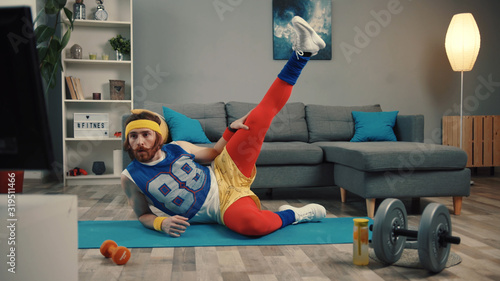 LOS ANGELES, CALIFORNIA, 10 OCTOBER, 2019: Funny fitness vlogger exercising and training at home. Sportive young man in retro clothes shooting a sports vlog. Motivation and sport concept. photo