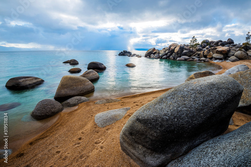 Granite boulders line a beautiful beach with clouds overhead on the east shore of Lake Tahoe, Nevada photo