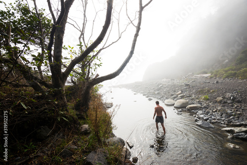 A man wades down Buck Creek in the fog while backpacking the Lost Coast Trail in the King Range National Conservation Area of Northern California. This seciton of trail is impassable at high tide. photo