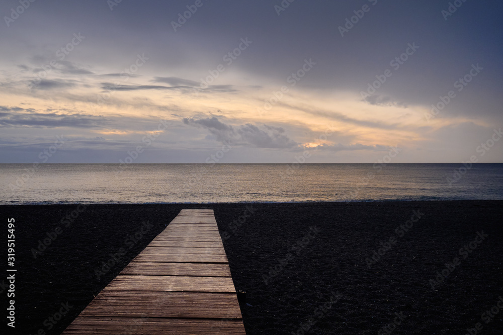 Beach of Calahonda in Costa del Sol, wooden boardwalk leading to Mediterranean Sea, fluffy cloudy sky romantic morning or evening sunrise. Spain, Andalusia.