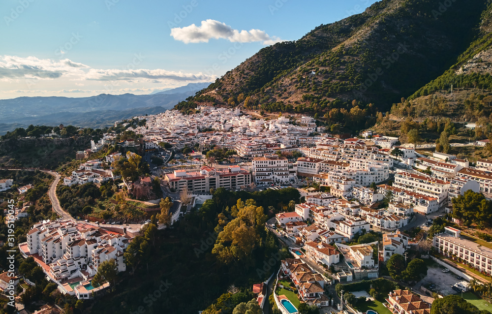 Aerial photo distant view charming Mijas pueblo, typical Andalusian white-washed mountain village, houses rooftops, small town located on hillside Province of Málaga, Costa del Sol, Europe, Spain
