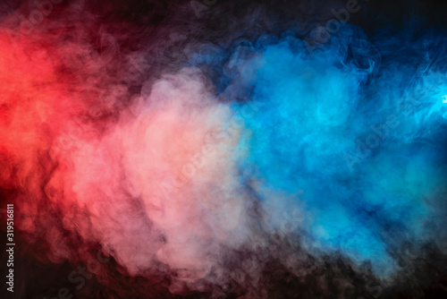 Backlit colorful smoke texture in red blue on a black background. © igorgeiger