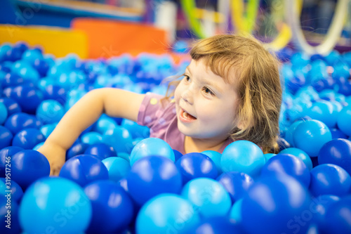 Happy little girl child in colourful blue plastic balls pool.