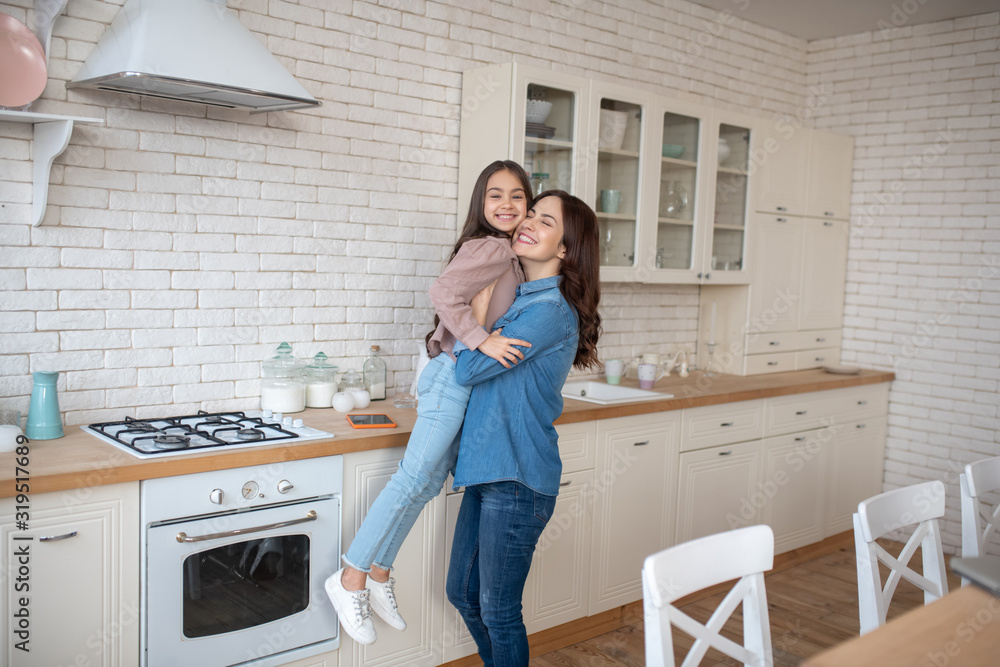Mom cuddles and raises her daughter, with her eyes closed. Mom cuddles and raises her daughter, with her eyes closed.