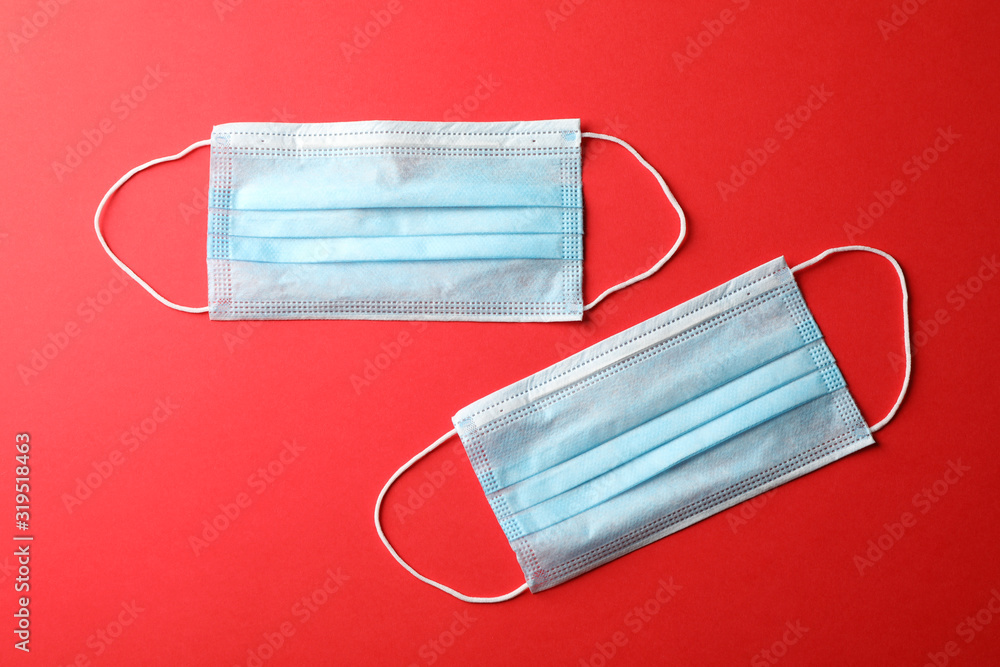 Protective mask on red background, top view, space for text.Virus protection. Healthcare and medical concept Protective mask on red background, top view, space for text.Virus protection. Healthcare and medical concept