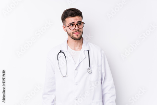 Young caucasian doctor man isolated confused, feels doubtful and unsure.