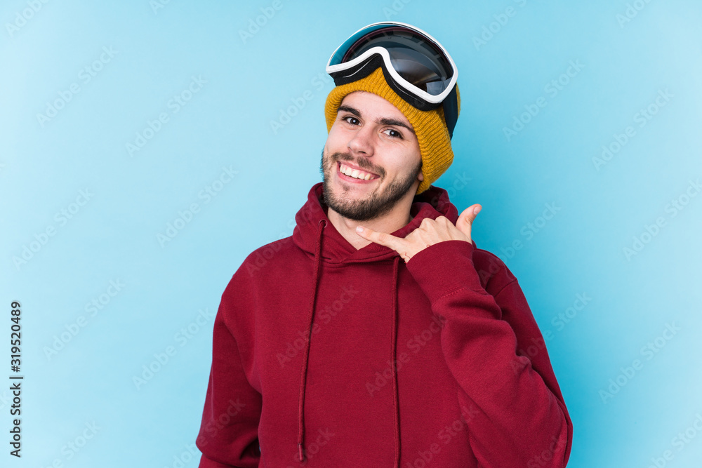 Young caucasian man wearing a ski clothes isolated showing a mobile phone call gesture with fingers. Young caucasian man wearing a ski clothes isolated showing a mobile phone call gesture with fingers.