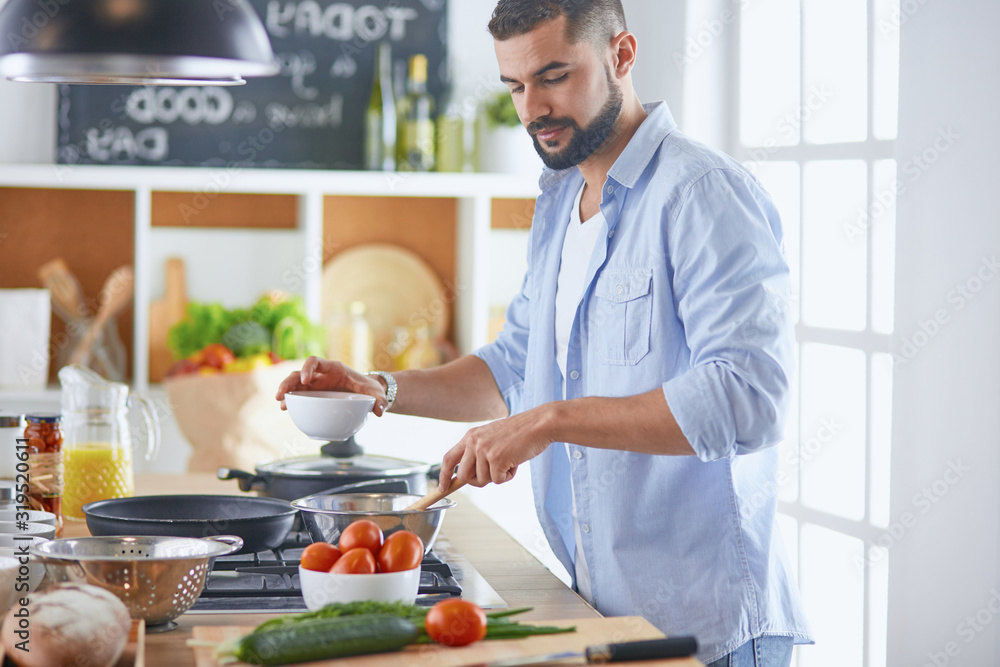 Smiling and confident chef standing in large kitchen Smiling and confident chef standing in large kitchen
