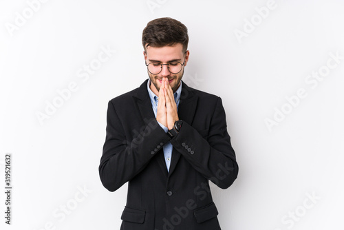 Young caucasian business man posing in a white background isolated Young caucasian business man holding hands in pray near mouth, feels confident.
