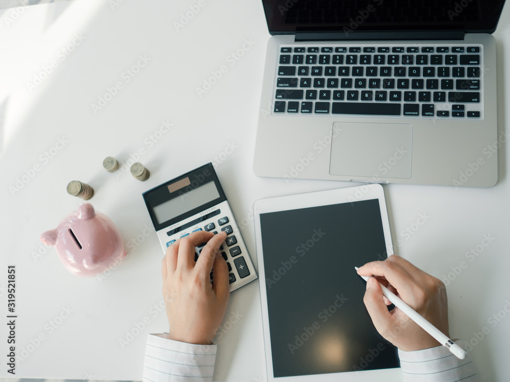 piggy bank and business women working and calculate expenses with calculator and laptop. stacks of coins. saving for investment and furure concept piggy bank and business women working and calculate expenses with calculator and laptop. stacks of coins. saving for investment and furure concept