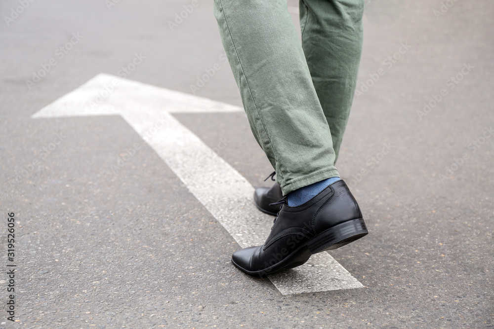 Young man going along road with arrow marking. Concept of choice Young man going along road with arrow marking. Concept of choice