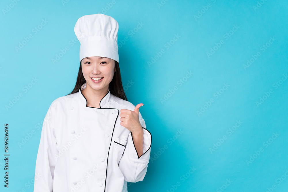 Young chinese chef woman isolated smiling and raising thumb up Young chinese chef woman isolated smiling and raising thumb up