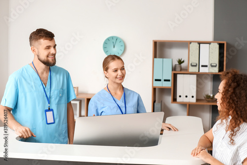 Male and female receptionists working at desk in clinic
