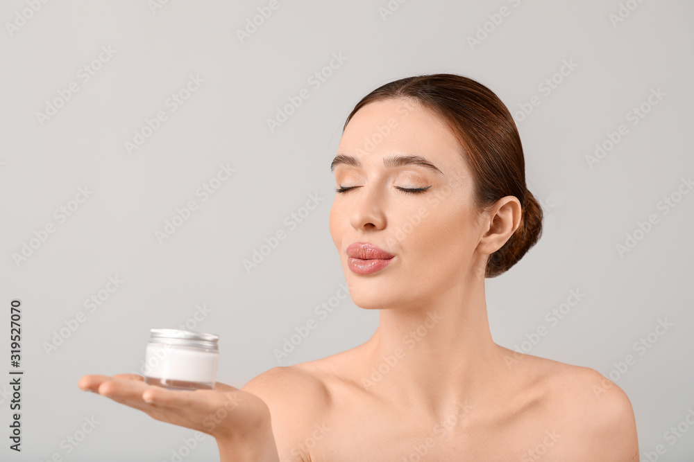Beautiful young woman with cream on light background Beautiful young woman with cream on light background