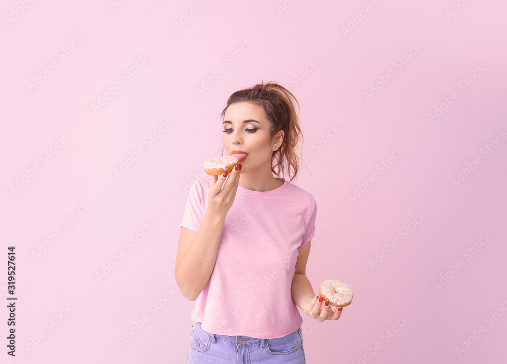 Beautiful young woman with donuts on color background