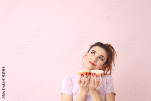 Thoughtful young woman with donuts on color background