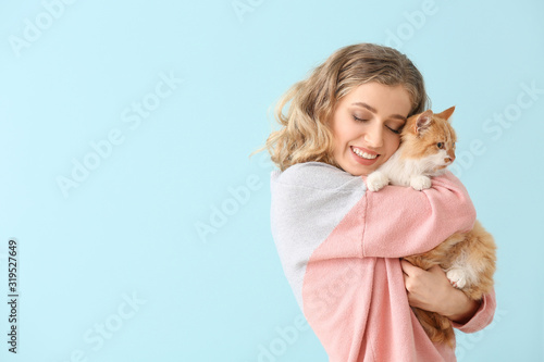 Beautiful young woman with cute cat on color background