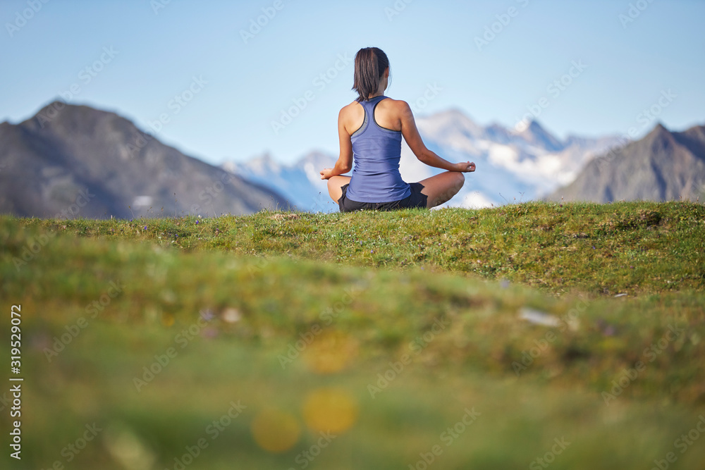 Woman meditating in the mountains, rear view