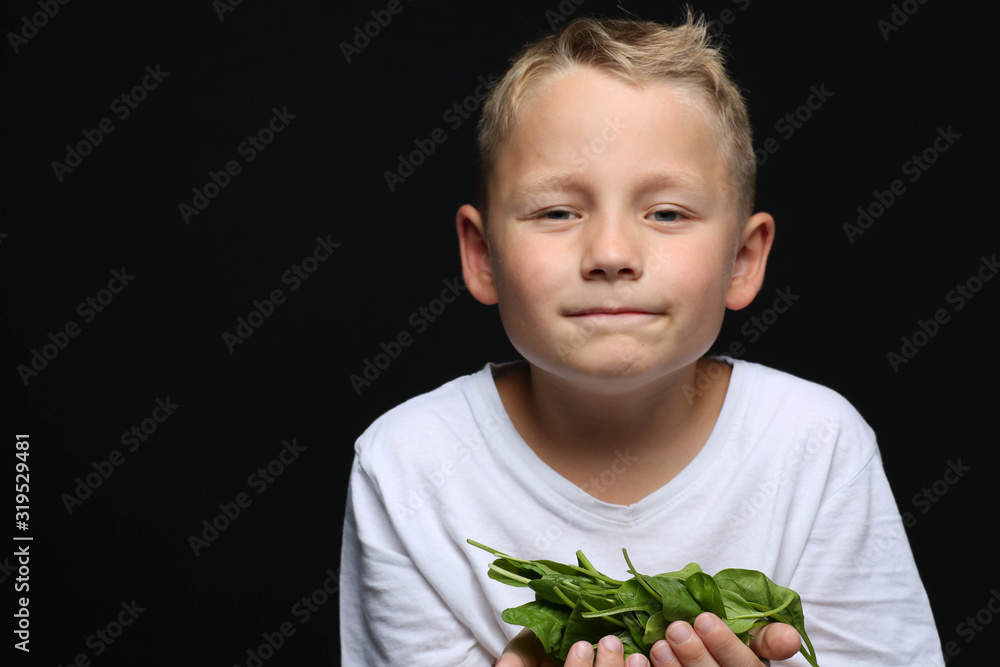 Little boy with spinach in his hands and does not like to eat it Little boy with spinach in his hands and does not like to eat it