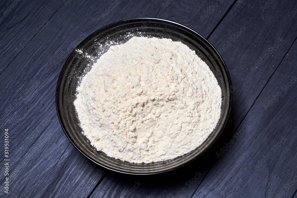 Plate with flour on a dark background.