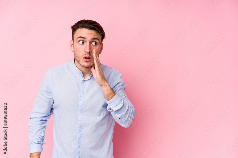 Young caucasian man posing in a pink background isolated is saying a secret hot braking news and looking aside Young caucasian man posing in a pink background isolated is saying a secret hot braking news and looking aside