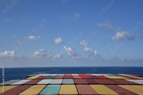 Containers loaded on the cargo container ship, she is sailing through calm blue sea.