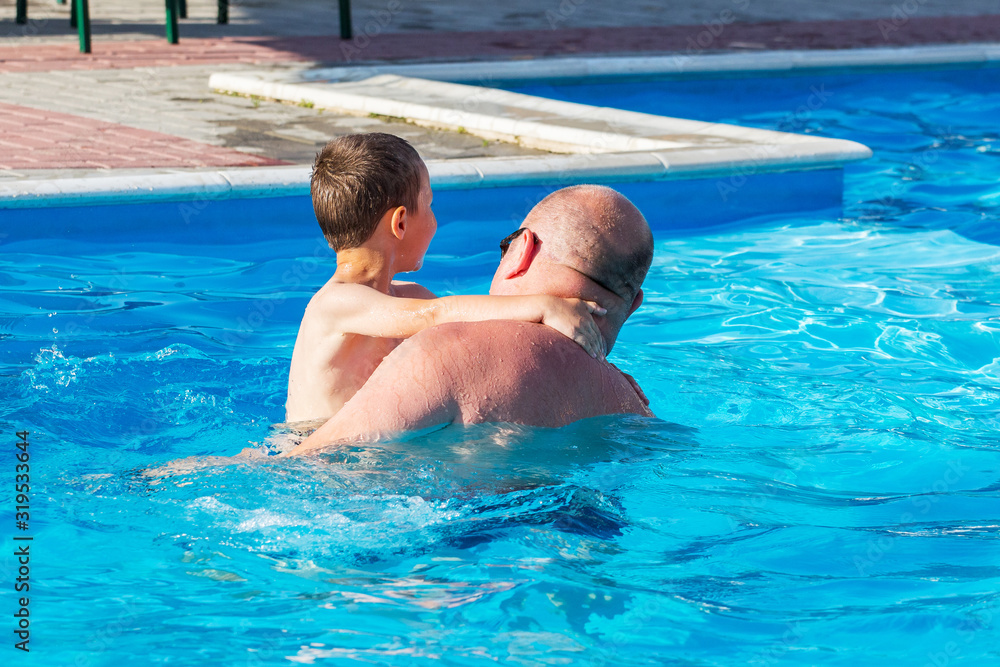 Father with son swim in swimming pool. Father loves son_