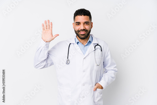 Young arabian doctor man isolated smiling cheerful showing number five with fingers.