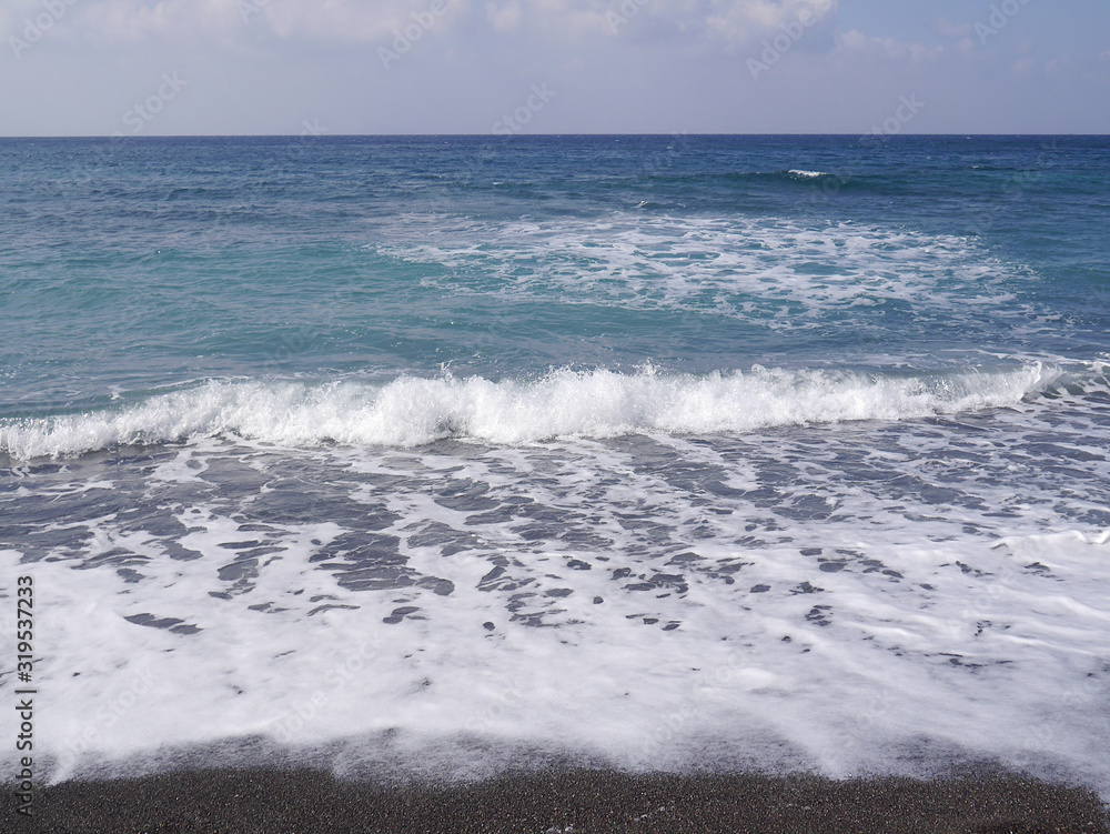 Seascape on the island of Santorini, Greece. Sea waves with foam on a sunny day.