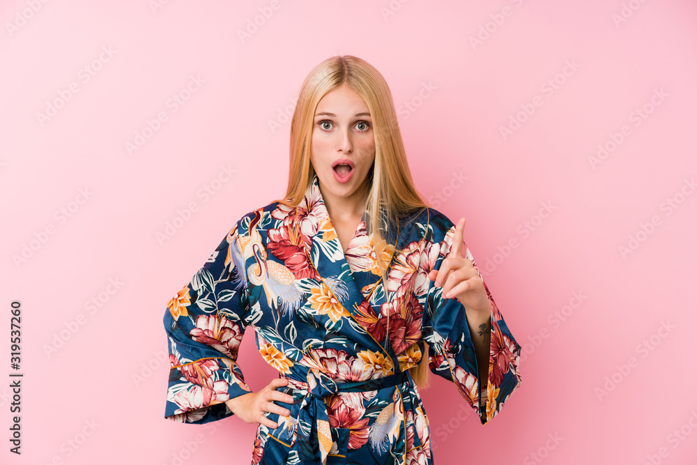 Young blonde woman wearing a kimono pajama having an idea, inspiration concept. Young blonde woman wearing a kimono pajama having an idea, inspiration concept.