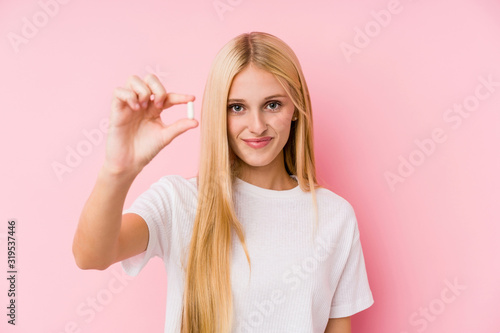Young blonde woman taking some pills isolated on a blackground