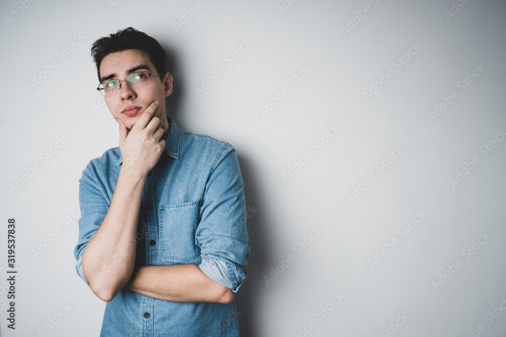 Pensive young guy in glasses and a denim shirt on a white background. Pensive young guy in glasses and a denim shirt on a white background.