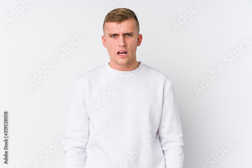 Young caucasian man on white background screaming very angry and aggressive.