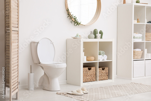 Modern toilet bowl near white wall in bathroom