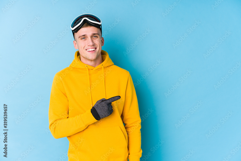 Young skier man smiling and pointing aside, showing something at blank space. Young skier man smiling and pointing aside, showing something at blank space.