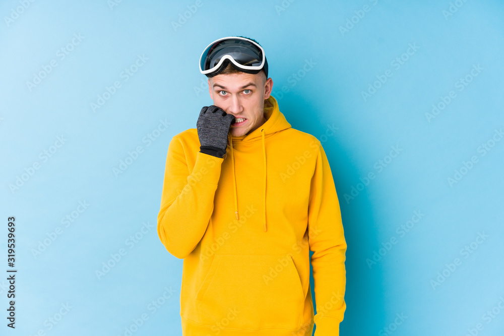 Young skier man biting fingernails, nervous and very anxious.