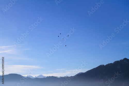 Air Balloons flying in blue sky over misty lake Lucern, Swirtzerland © Stockphototrends