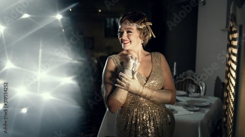 a woman in the image of 20s, looks like a frame from old films, on the head of the diodema a hairstyle wave, long gloves with ornaments, surrounded by light glare