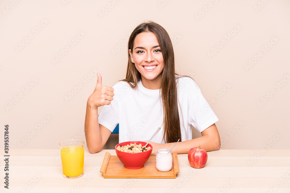 Young caucasian woman having a breakfast isolated smiling and raising thumb up Young caucasian woman having a breakfast isolated smiling and raising thumb up