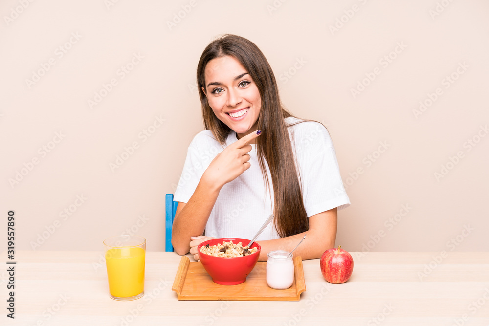 Young caucasian woman having a breakfast isolated smiling and pointing aside, showing something at blank space. Young caucasian woman having a breakfast isolated smiling and pointing aside, showing something at blank space.
