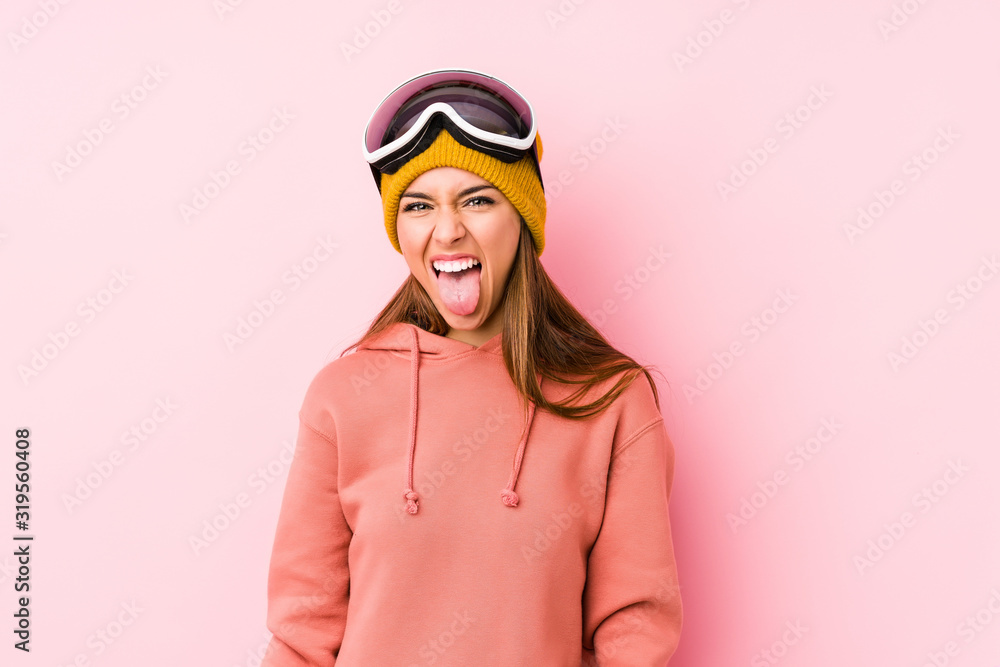 Young caucasian woman wearing a ski clothes isolated funny and friendly sticking out tongue.