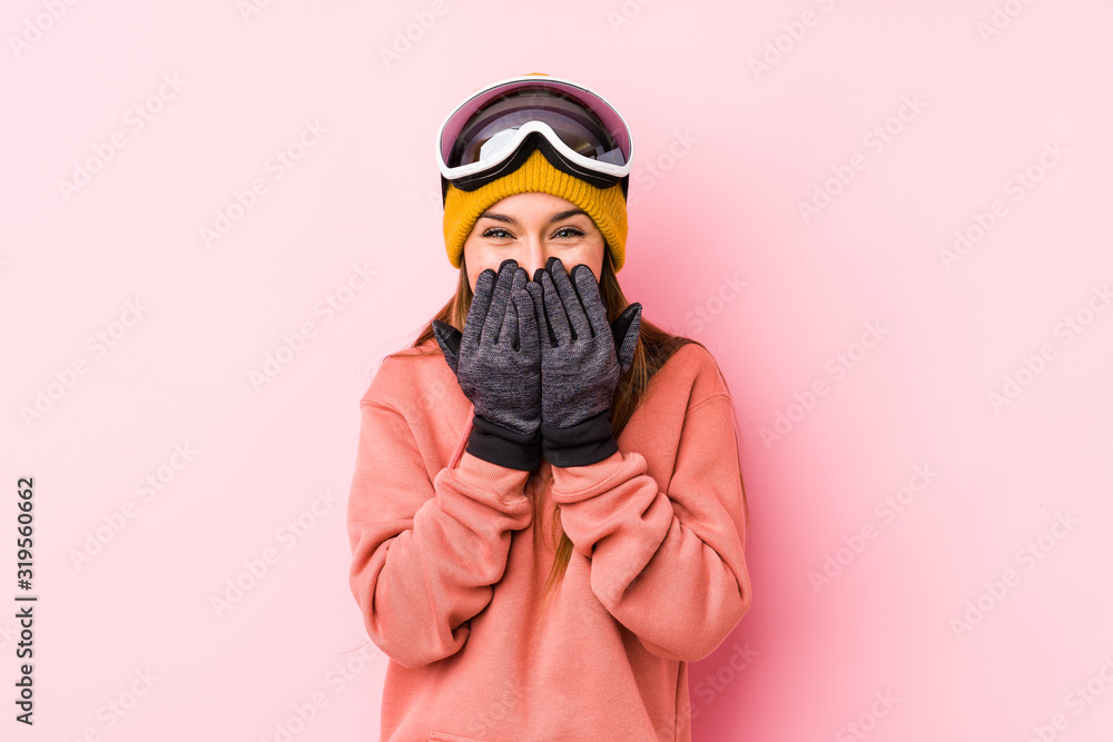 Young caucasian woman wearing a ski clothes isolated laughing about something, covering mouth with hands. Young caucasian woman wearing a ski clothes isolated laughing about something, covering mouth with hands.