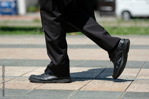 朝の駅前で革靴とスーツで歩く男性の足元