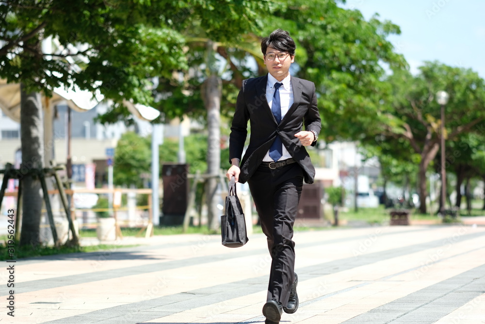朝の駅前でスーツ姿の眼鏡をかけた代の日本人の男性が走る Stock Foto Adobe Stock