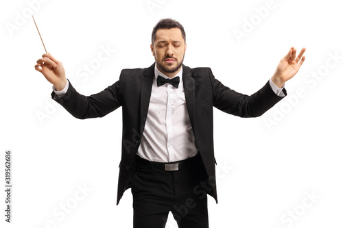 Young male conductor with closed eyes conduction with baton photo