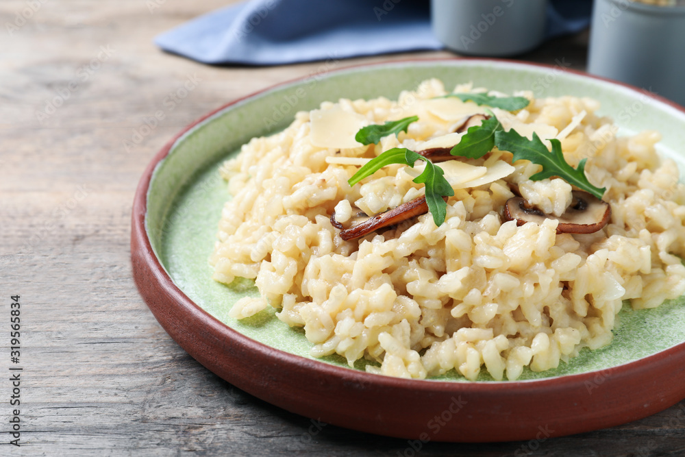 Delicious risotto with cheese and mushrooms on wooden table, closeup Delicious risotto with cheese and mushrooms on wooden table, closeup