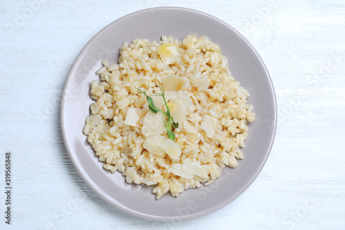 Delicious risotto with cheese on white wooden table, top view